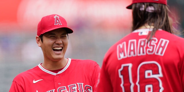 Los Angeles Angels' Shohei Ohtani, left, laughs as he talks to Brandon Marsh prior to a baseball game against the Texas Rangers Sunday, July 31, 2022, in Anaheim, Calif.
