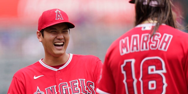 Los Angeles Angels' Shohei Ohtani, left, laughs as he talks to Brandon Marsh prior to a baseball game against the Texas Rangers Sunday, July 31, 2022, in Anaheim, Calif.