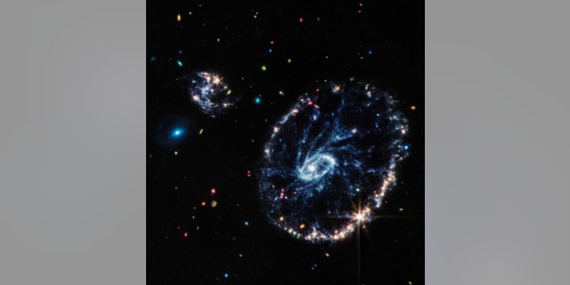 This image from Webb's Mid-Infrared Instrument (MIRI) shows a group of galaxies, including a large, distorted ring-shaped galaxy known as the Cartwheel.