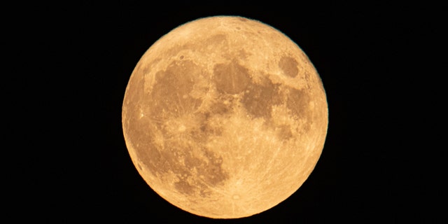 يرتفع القمر الكامل لسمك الحفش في أغسطس خلف جبل Hortiatis ومدينة Thessaloniki فوق البحر ، ويطلق عليه مراقبو السماء Blue Moon. 