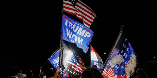 Supporters of former President Donald Trump gather and wave flags outside his home in Palm Beach, Fla., after FBI agents conducted a raid on Monday, Aug. 8, 2022.