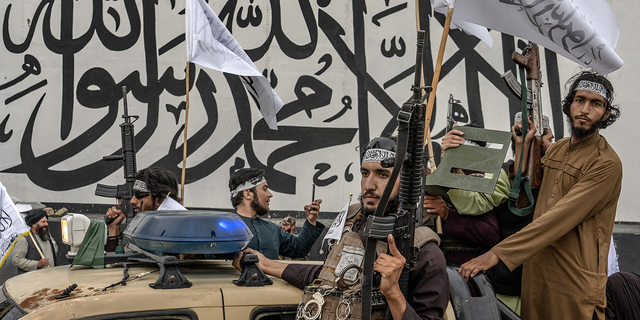 Taliban fighters take up arms in front of the US embassy in Kabul, Afghanistan, on Monday, August 15, as they celebrate the one year anniversary of occupying the Afghan capital.