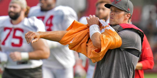 Tampa Bay Buccaneers quarterback Tom Brady puts on his jersey during practice with the Miami Dolphins on Aug. 10, 2022, in Tampa, Florida.