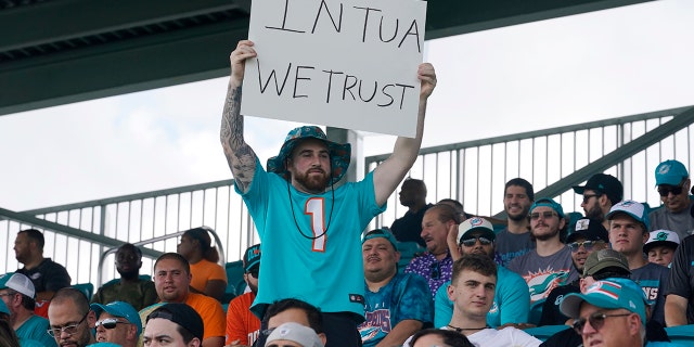 A Dolphins fan holds a sign in support of quarterback Tua Tagovailoa during drills at the team's practice facility, Saturday, July 30, 2022, in Miami Gardens, Florida.