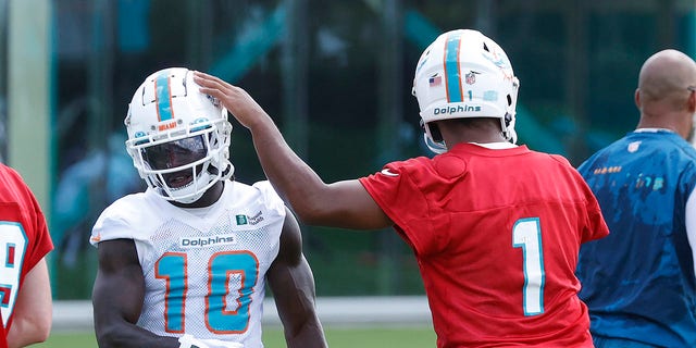 Tua Tagovailoa #1 taps the helmet of Tyreek Hill #10 of the Miami Dolphins between practices during the Miami Dolphins Compulsory Minicamp at the Baptiste Health Training Complex in Miami Gardens, Florida on June 1, 2022.
