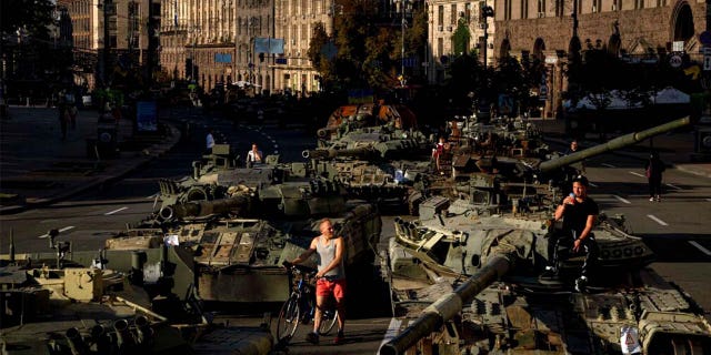 People walk around destroyed Russian military vehicles installed in downtown Kyiv, Ukraine, Wednesday, Aug. 24, 2022.