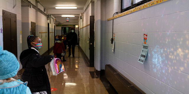 A student reflects a lunch bag on a hallway wall as COVID-19 restrictions are lifted in Philadelphia, Pennsylvania.