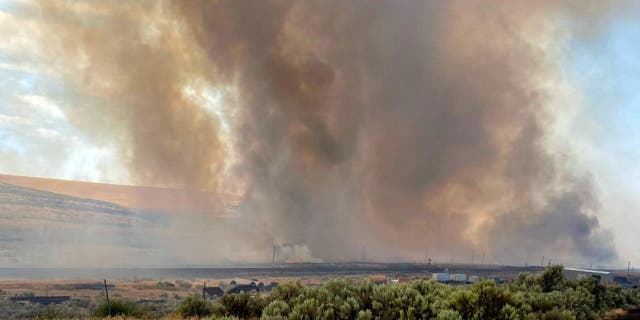 This photo provided by the Washington State Department of Transportation shows smoke from a wildfire burning on Thursday, Aug. 4, 2022. Sheriff's officials are telling residents in the town of Lind in eastern Washington to evacuate because of a growing wildfire south of town that was burning homes.