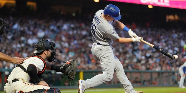 Los Angeles Dodgers' Will Smith, right, hits an RBI double in front of San Francisco Giants catcher Joey Bart during the fifth inning of a baseball game in San Francisco, Monday, Aug. 1, 2022. 