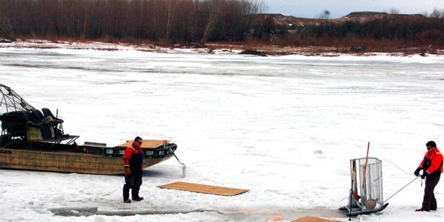 FILE - In this Jan. 19, 2015 photo, cleanup workers cut holes into the ice on the Yellowstone River near Crane, Montana.
