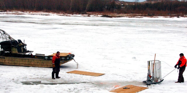 FILE - In this Jan. 19, 2015 photo, cleanup workers cut holes into the ice on the Yellowstone River near Crane, Montana.