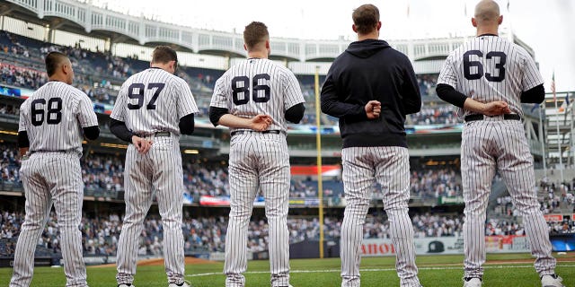 Manny Bañuelos #68 de los New York Yankees, Ron Marinaccio #97 de los New York Yankees, Clarke Schmidt #86 de los New York Yankees, Lucas Luetge #63 de los New York Yankees defienden el himno nacional antes de enfrentar a los Tigres de Detroit en Yankee Stadium el 3 de junio de 2022 en la ciudad de Nueva York.