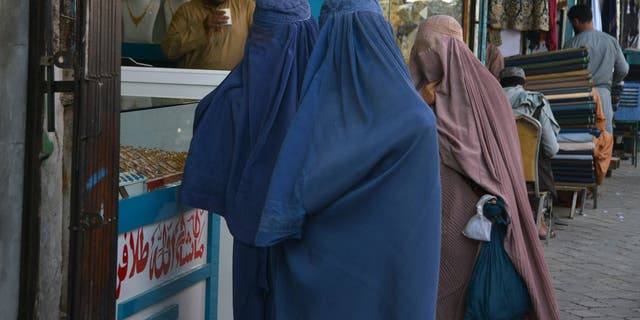 아프가니스탄 여성들이 칸다하르의 시장을 따라 걸을 때 부르카를 착용합니다.