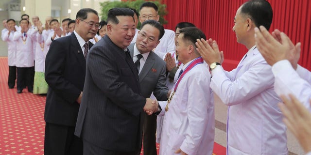 In this photo provided by the North Korean government, North Korean leader Kim Jong Un shakes hands with a health official in Pyongyang, North Korea, Wednesday, August 10, 2022. 
