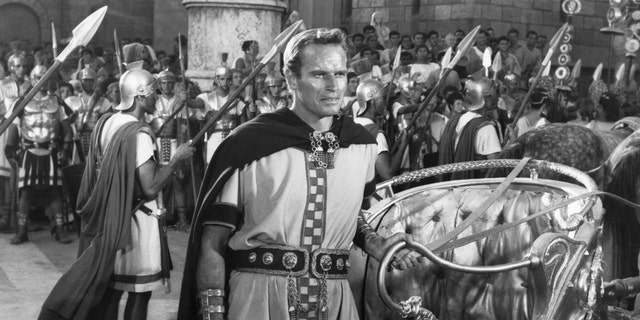 Charlton Heston as Ben-Hur stands by his chariot during a victory parade in Rome in honor of Quintus Arrius (Jack Hawkins), a great naval hero. "Ben-Hur," MGM's spectacular film based on General Lew Wallace's classic novel, had a cast of thousands headed by Charlton Heston, Jack Hawkins, Stephen Boyd, Haya Harareet, Hugh Griffith, Martha Scott, Cathy O'Donnell, Sam Jaffe and Finlay Currie. It was directed by William Wyler and produced by Sam Zimbalist, 1959.
