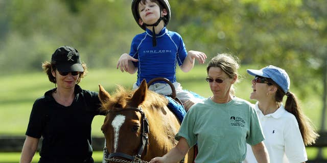 A boy with cerebral palsy partakes in equine therapy on Nov. 19, 2003 in Coconut Creek, Florida. A nonprofit program is making equine therapy available to children with cerebral palsy of low-income families in Venezuela.