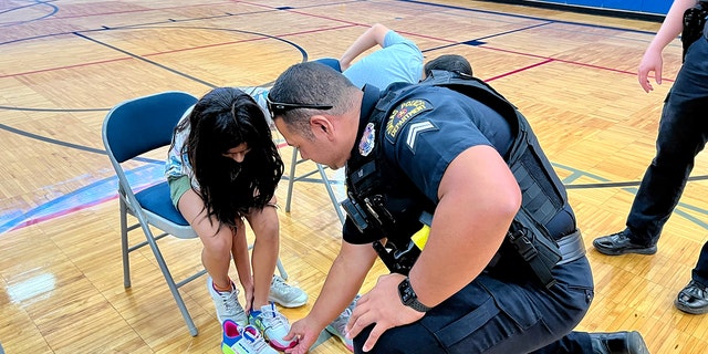 A police officer in Dallas, Texas, helps students try on new sneakers ahead of back-to-school time this year. 