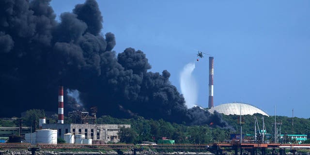 Un hélicoptère inonde la base de superpétroliers de Matanzas alors que les pompiers tentent d'éteindre un incendie qui s'est déclaré lors d'un orage la nuit précédente à Matanzas, Cuba, le 6 août 2022 (AP Photo/Ramon Espinosa)