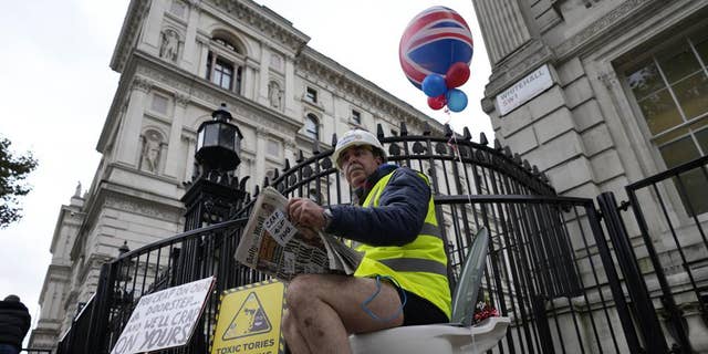 An activist sits on a toilet at the entrance to Downing Street to protest against raw sewage dumping in the rivers and seas around the UK in London, on Oct. 26, 2021.