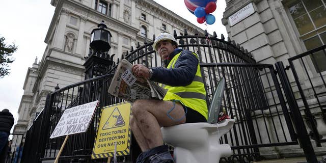 An activist sits on a toilet at the entrance to Downing Street to protest against raw sewage dumping in the rivers and seas around the UK in London, on Oct. 26, 2021.