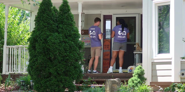 Two door-knockers seek to talk with prospective voters about a proposed amendment to the Kansas Constitution that would allow legislators to further restrict or ban abortion.