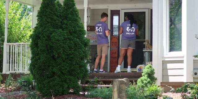 Two door-knockers seek to talk with prospective voters about a proposed amendment to the Kansas Constitution that would allow legislators to further restrict or ban abortion.
