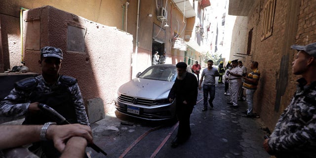 People and policemen stand near the scene where a deadly fire broke out at the Abu Sifin church in Cairo's Imbaba neighborhood on Sunday.