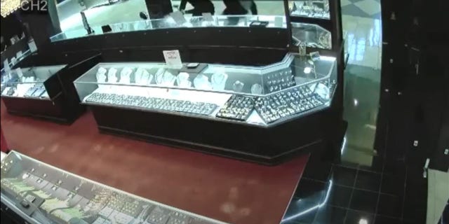 Surveillance video shows the men shattering glass display cases holding high-end watches with what appear to be hammers.