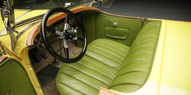 The car features creamy yellow paint and green leather upholstery.
