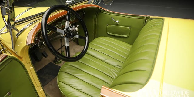 The car features creamy yellow paint and green leather upholstery.