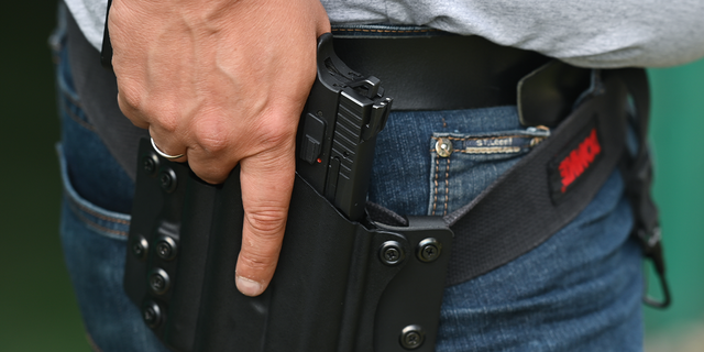 Photo showing man with holstered handgun at shooting range