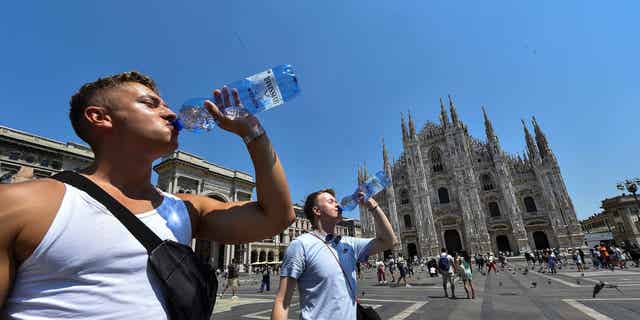 Pictured: Men drinking water to stay hydrated during heat wave in Milan, Italy, on July 21, 2022.