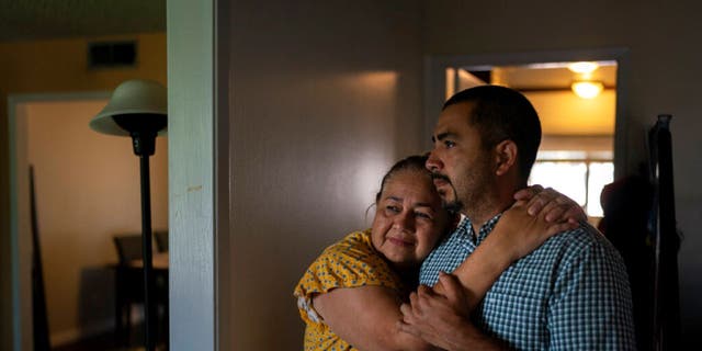Ana Sandoval, mother of Eyvin Hernandez, a Los Angeles attorney who has been detained for five months in Venezuela, hugs her son Henry Martinez, Hernandez's half-brother, while posing for photos in Compton, Calif.,