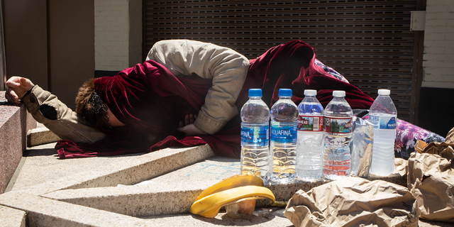 A homeless person sleeps in the sun during a heatwave in Portland, Ore., on June 28, 2021.