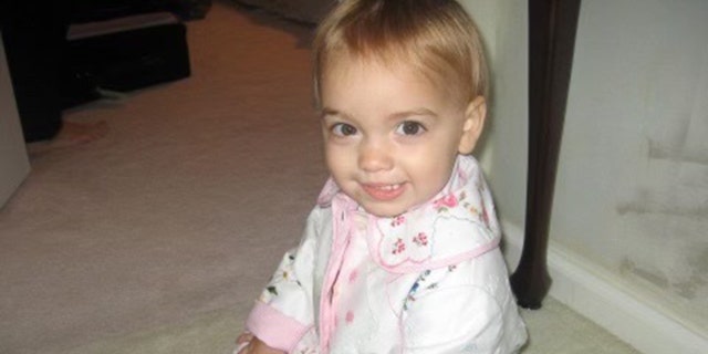 Sydney sits on the floor of her family's home when she was a baby.