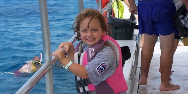 Young Sydney Stanley is shown posing on a boat during a family vacation.