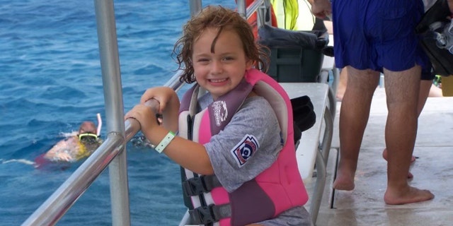 Young Sydney Stanley is shown posing on a boat during a family vacation.