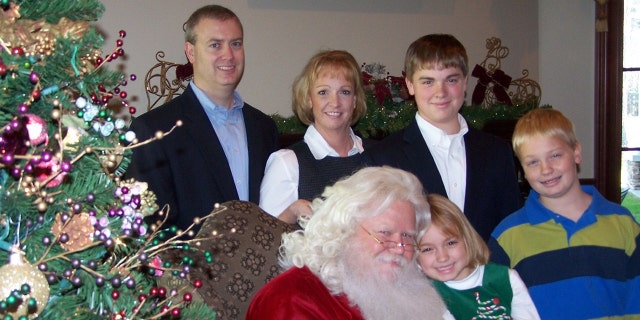 The Stanley family — Mike (at far left), Jenny, Logan, Mason and Sydney (in front) — pose with Santa Claus for a family Christmas photo. 