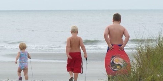 Georgia siblings Sydney (at far left), Mason and Logan walk along a beach when they were young children.