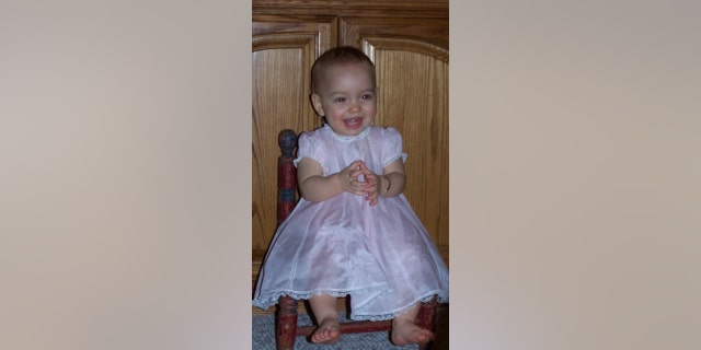 Sydney as a baby, wearing an adorable pink dress.