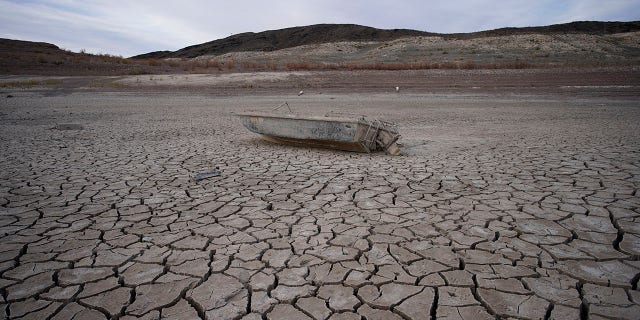 A formerly sunken boat sits on cracked earth hundreds of feet from the shoreline of Lake Mead at the Lake Mead National Recreation Area on May 10, 2022, near Boulder City, Nevada.