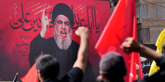 Hezbollah leader Sheik Hassan Nasrallah speaks via video link as his supporters raise their hands during the Shiite holy day of Ashoura in the southern suburb of Beirut, Lebanon, Aug. 9, 2022. 