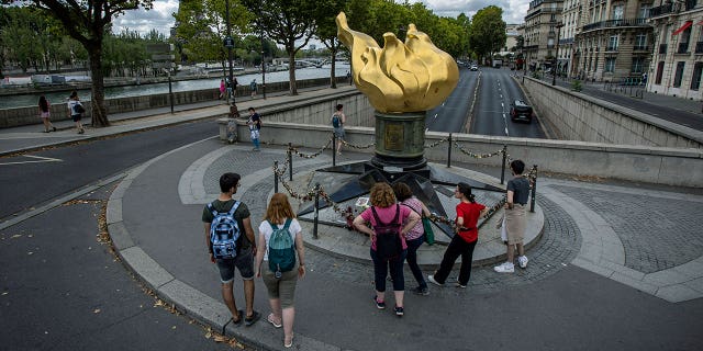People stand by the gilded statue Flame of Liberty that serves as an unofficial shrine to Princess Diana, Monday Aug. 22, 2022 in Paris. It has been nearly 25 years since Princess Diana died in a high-speed car crash in Paris. The French doctor who treated her at the scene has recounted what happened. Dr. Frederic Mailliez told The Associated Press how he tried to save her on that night of Aug. 31, 1997. He remembers speaking English to her, giving here a respiratory bag and calling the emergency services. Diana, her companion Dodi Fayed and their chauffeur died in a car crash in the Alma Tunnel next to the Seine River.