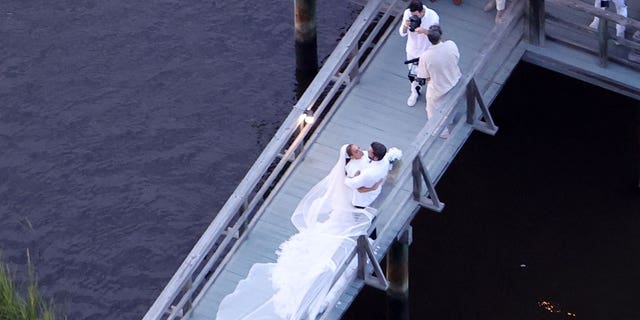 Ben Affleck and Jennifer Lopez pose for pictures at their wedding on a boardwalk.