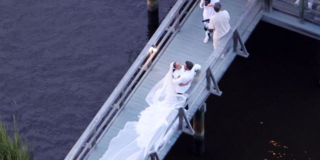 Ben Affleck and Jennifer Lopez pose for pictures at their wedding on a boardwalk.