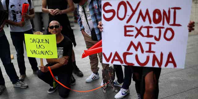 Protestors hold up signs reading "Release the vaccines" and "I am Moni, I demand my vaccine" outside the Health Secretary building, in Mexico City, Mexico, Mexico, on July 26, 2022.