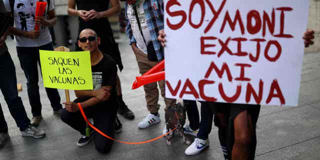 Protesters hold up signs reading "Release vaccines" and "I'm Moni, I demand my vaccine" in front of the building of the Secretary of Health, in Mexico City, Mexico, Mexico, on July 26, 2022.
