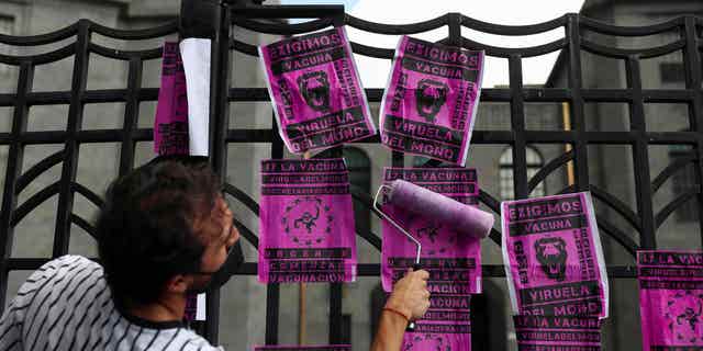 Un manifestante coloca carteles en protesta por el manejo del virus de la viruela símica en México, frente al edificio de la Secretaría de Estado, en la Ciudad de México, México, el 26 de julio de 2022.
