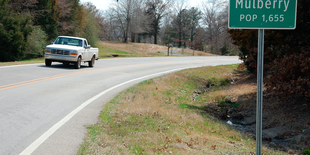 A truck drives near a population sign in Mulberry, Ark.