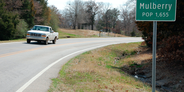 A truck drives near a population sign in Mulberry, Ark.